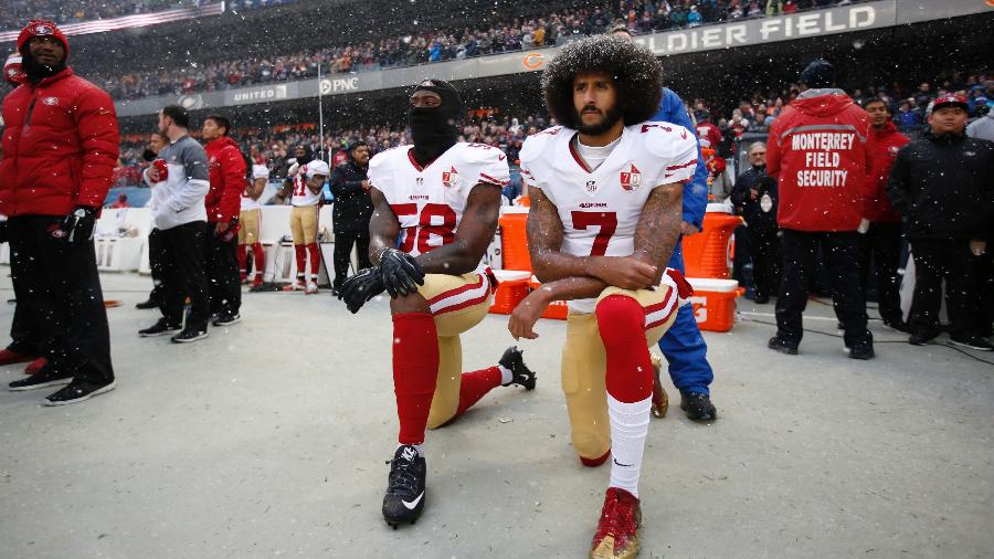 Colin Kaepernick (dir) e Eli Harold ajoelham na hora da execução do hino dos EUA no jogo entre San Francisco 49ers e Chicago Bears na NFL em 2018